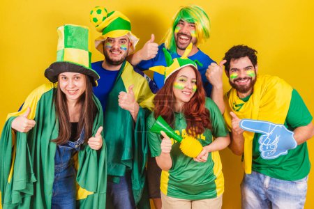 Photo for Group of friends, soccer fans from brazil, using brazil flag, doing thumbs up, approval, happy. - Royalty Free Image