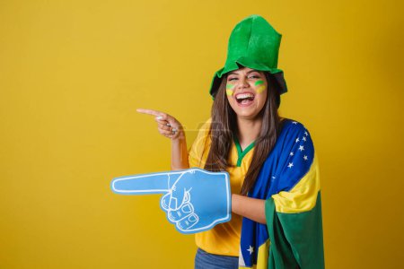 Téléchargez les photos : Femme supporter du Brésil, Coupe du monde 2022, pointant avec un doigt en mousse vers la gauche. - en image libre de droit