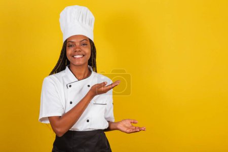 Foto de Joven mujer afro-brasileña, chef, presentando algo a la derecha, señalando algo. - Imagen libre de derechos