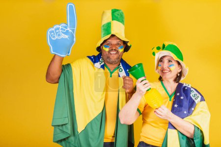 Téléchargez les photos : Couple, femme rousse et homme noir, fans de football brésilien. robes pour le monde. - en image libre de droit