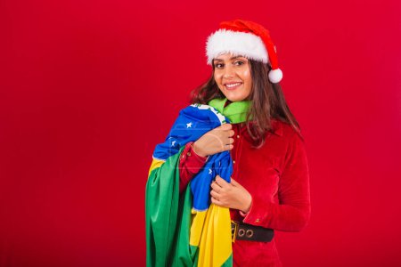 Photo for Beautiful Brazilian woman dressed in Christmas clothes, Santa Claus. holding brazil flag. - Royalty Free Image