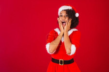 Photo for Beautiful black brazilian woman, dressed as santa claus, mama claus, hands on face, incredible - Royalty Free Image