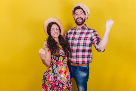 Photo for Beautiful couple dressed in typical clothes for a Festa Junina. Arraia de Sao Joao. Celebrating, victory, cheering. - Royalty Free Image