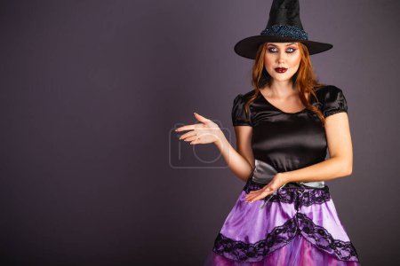 Téléchargez les photos : Répétition d'Halloween, femme caucasienne en costume de sorcière. présenter quelque chose avec leurs mains. - en image libre de droit