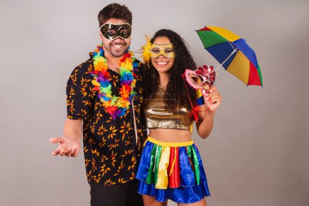 Photo for Brazilian couple, with carnival clothes. holding carnival accessories, umbrella and mask. - Royalty Free Image