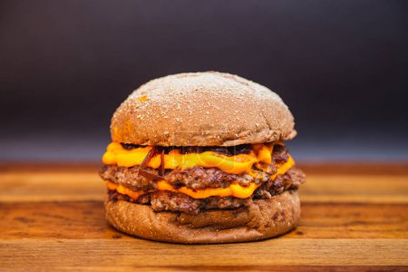 Foto de Deliciosa hamburguesa doble de ternera con queso cheddar y cebolla caramelizada. hamburguesa de carne. Pan australiano - Imagen libre de derechos