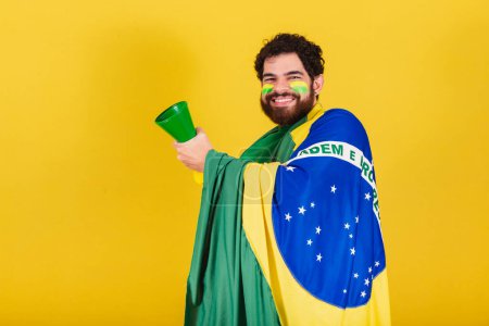 Photo for Man, brazilian, bearded, soccer fan from brazil, using his horn in a world cup match, partying, making noise. - Royalty Free Image