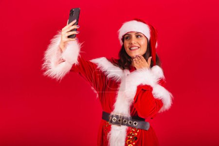 Téléchargez les photos : Femme brésilienne vêtue de vêtements de Noël, le Père Noël. prise de photo autoportrait avec smartphone. - en image libre de droit