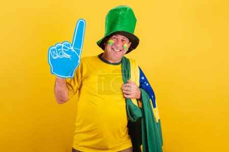 Photo for Adult man, soccer fan from brazil, wearing flag, with foam finger smiling for photo. - Royalty Free Image