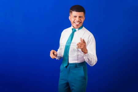 Foto de Hombre negro brasileño, vestido con ropa de negocios y corbata azul. hombre de negocios. sonriendo con las manos en la presentación. - Imagen libre de derechos