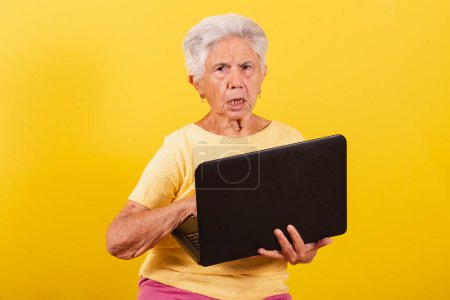 Photo for Old lady holding notebook, laptop. inclusion of the elderly in the digital environment. - Royalty Free Image