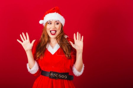 Photo for Beautiful Brazilian red-haired woman, dressed in Christmas clothes, Santa Claus. expression of surprise. - Royalty Free Image