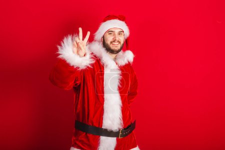 Photo for Caucasian, Brazilian man dressed in Christmas outfit, Santa Claus. peace and love, fingers for photo. Selfie. - Royalty Free Image