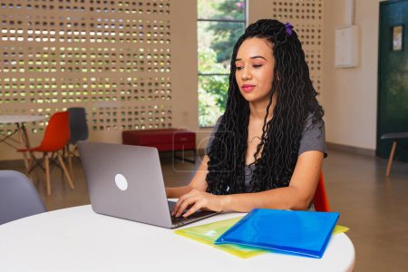 Téléchargez les photos : Jeune femme noire, brésilien, étudiante travaillant sur ordinateur portable, en ligne. - en image libre de droit