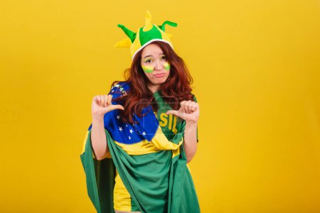 Téléchargez les photos : Femme caucasienne, rousse, fan de football de Brésil, pouce baissé, aversion, mauvais, négatif. - en image libre de droit