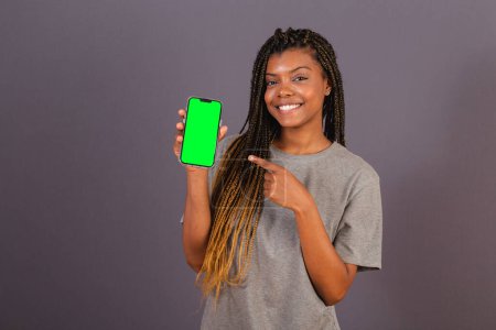 Foto de Joven mujer afro brasileña mostrando la pantalla del teléfono inteligente. espacio para anuncios, aplicaciones, móviles. - Imagen libre de derechos