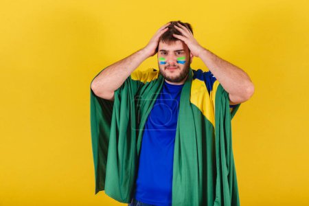 Foto de Hombre caucásico brasileño, aficionado al fútbol brasileño, manos en la cabeza, preocupado, ansioso. - Imagen libre de derechos