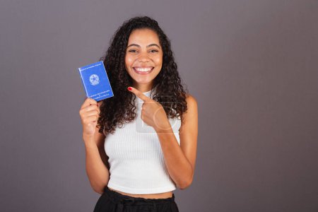 Foto de Joven brasileña negra sosteniendo billetera de trabajo. CLT, Tarjeta de Trabajo y Seguridad Social - Imagen libre de derechos