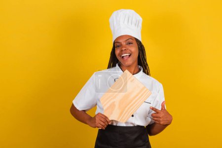 Foto de Joven mujer brasileña afro, cocinera, sosteniendo tablero de madera para la gastronomía. - Imagen libre de derechos