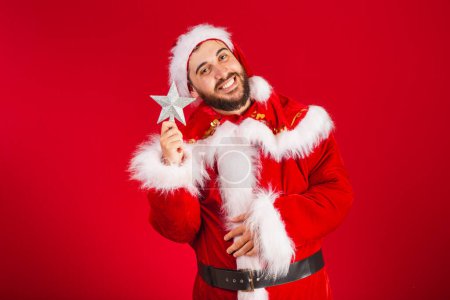 Téléchargez les photos : Homme brésilien, habillé en santa claus vêtements, tenant étoile de Noël. - en image libre de droit