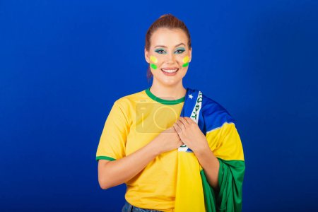 Photo for Caucasian woman, redhead, Brazilian soccer fan, Brazilian, blue background, singing national anthem, gratitude - Royalty Free Image