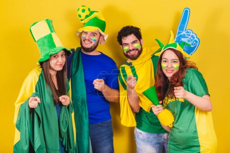 Téléchargez les photos : Groupe d'amis, fans de football brésilien, portant le drapeau brésilien, pointant vers la caméra, vous choisissant. - en image libre de droit