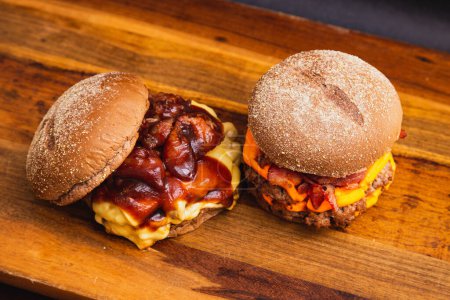 Téléchargez les photos : Deux hamburgers faits à la main sur une planche en bois, faite avec du bœuf. Sauce au bacon, fromage et barbecue. - en image libre de droit