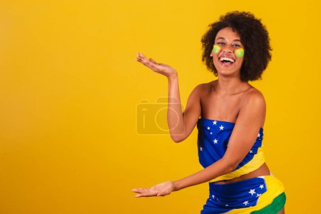 Photo for Young black woman brazilian soccer fan. presenting some product or information on the side - Royalty Free Image