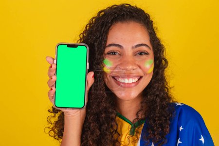 Photo for Young black Brazilian, soccer fan. showing cellphone screen, smartphone. App, mobile. close-up photo. - Royalty Free Image