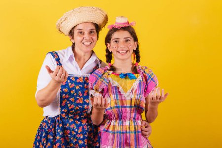 Foto de Abuela y nieta vestidas con ropa típica de Festa Junina. Llamar con las manos, invitar, venir aquí. - Imagen libre de derechos
