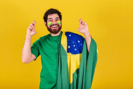 Photo for Caucasian man with beard, brazilian, soccer fan from brazil, fingers crossed, wishing, be lucky. Prize draw. - Royalty Free Image