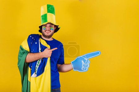Téléchargez les photos : Homme caucasien brésilien, fan de football brésilien, chapeau, en utilisant la mousse doigt à droite. - en image libre de droit