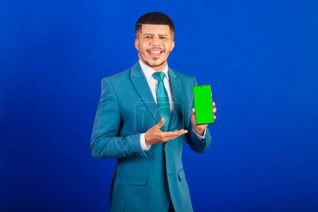 Téléchargez les photos : Homme noir brésilien, vêtu d'un costume et cravate bleue. homme d'affaires. écran et application smartphone - en image libre de droit