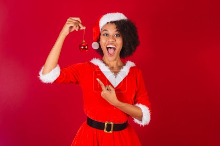 Téléchargez les photos : Belle femme brésilienne noire, habillée en Père Noël claus, maman claus, tenant décoration de Noël - en image libre de droit
