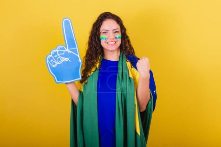 Photo for Woman soccer fan, fan of Brazil, happy and smiling. Cheering for the world cup, wearing foam glove. - Royalty Free Image