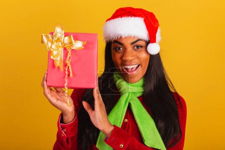 Photo for Beautiful black Brazilian woman, dressed in christmas clothes, santa claus, closeup photo with red gift. - Royalty Free Image