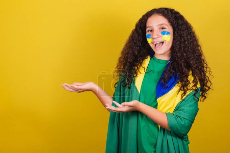 Photo for Brazilian Caucasian girl, soccer fan, presenting to the side, showing negative space for text, advertisement, advertisement, .World Cup. Olympics. - Royalty Free Image