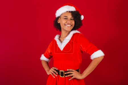 Téléchargez les photos : Belle femme brésilienne noire, habillée en Père Noël claus, maman claus, mains sur la taille - en image libre de droit