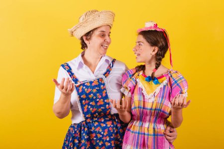 Photo for Grandmother and granddaughter dressed in typical Festa Junina clothes. Calling with the hands, inviting, come here. - Royalty Free Image