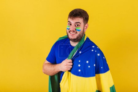 Photo for Caucasian brazilian man, soccer fan from brazil, wearing brazil flag cape. - Royalty Free Image