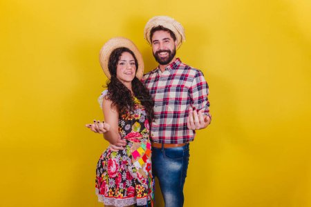 Foto de Hermosa pareja vestida con ropa típica para una Festa Junina. Arraia de Sao Joao. Llamado con las manos. invitando. - Imagen libre de derechos