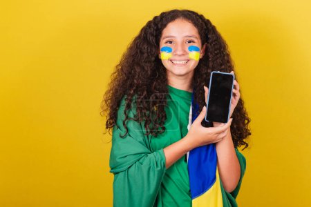 Photo for Brazilian Caucasian girl, soccer fan, holding cellphone, cellphone app, connected world, .World Cup. Olympics. - Royalty Free Image
