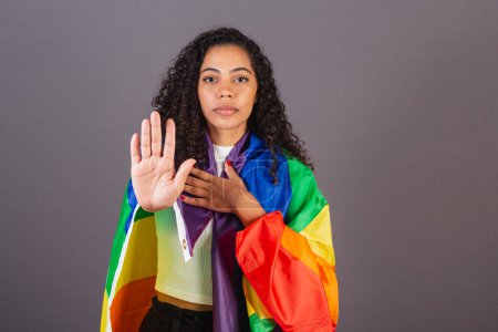 Téléchargez les photos : Jeune femme noire brésilienne, stop signe à la main, militantisme avec drapeau LGBT, diversité, lutte contre les préjugés. - en image libre de droit