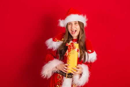 Photo for Caucasian, Brazilian woman in Christmas clothes, Santa Claus. holding yellow gift - Royalty Free Image