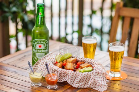 Photo for Pork, crackling, bacon. typical Brazilian snack, served with mayonnaise and chili sauce. Served with famous Heineken beer - Royalty Free Image