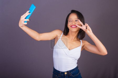 Téléchargez les photos : Jeune femme adulte du nord-est du Brésil. prise d'autoportrait, selfie, photo par smartphone. app, en ligne, technologie. - en image libre de droit