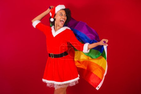 Téléchargez les photos : Belle femme brésilienne noire, habillée en Père Noël claus, maman claus, avec drapeau lgbt diversité, gays et lesbiennes - en image libre de droit