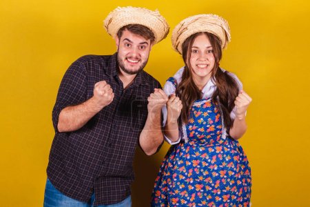 Photo for Beautiful couple wearing typical clothes for the Festa Junina. Cheering, celebrating, victory. - Royalty Free Image