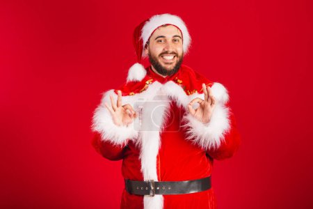 Photo for Brazilian man dressed in santa claus clothes, ok sign - Royalty Free Image