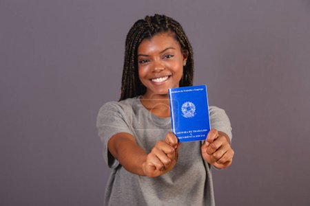 Téléchargez les photos : Jeune femme afro brésilienne titulaire d'une carte de travail et de la sécurité sociale. Document officiel, Ressources humaines, marché du travail. - en image libre de droit